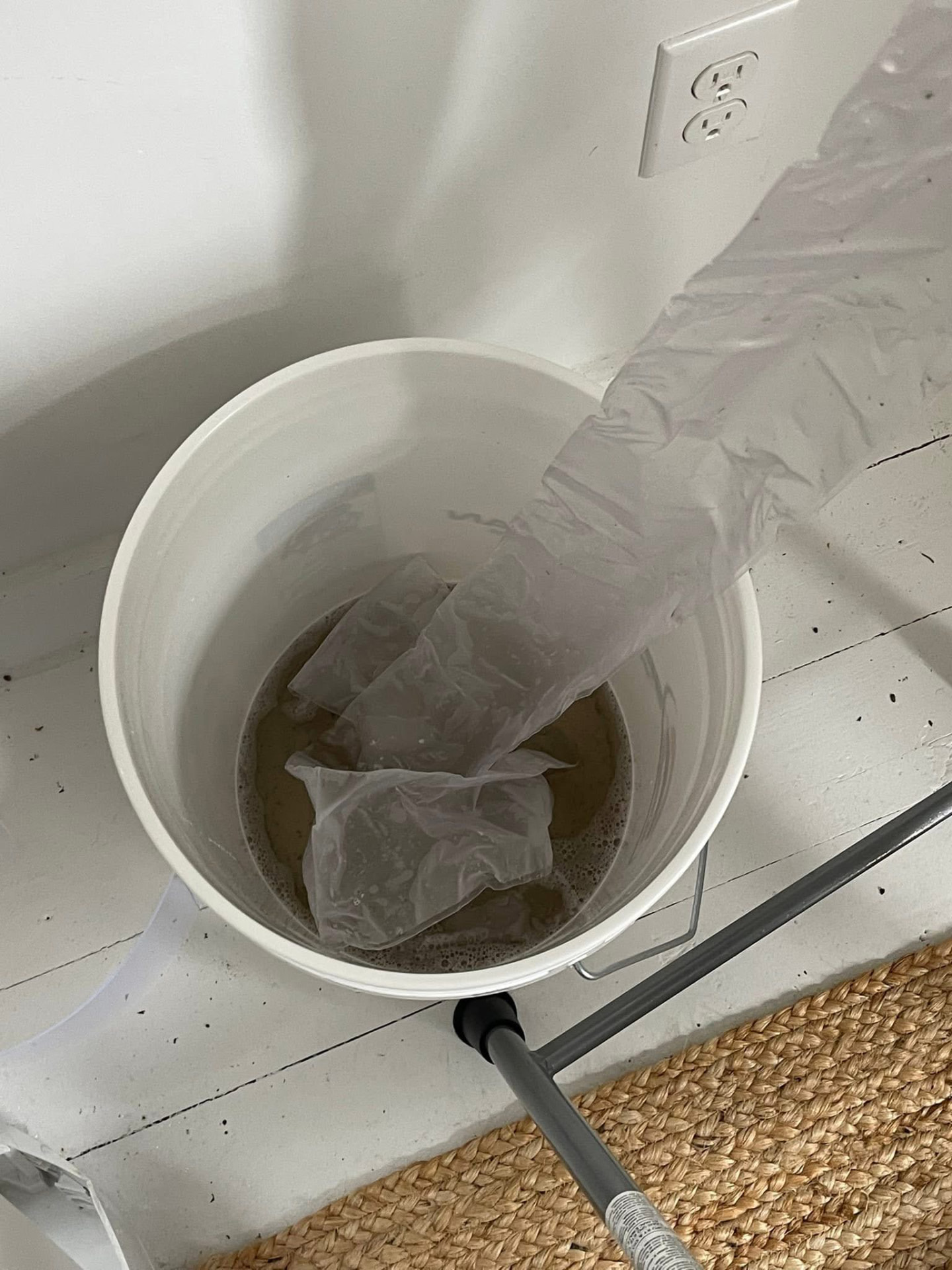 Bucket collecting dirty brown rinse water flushed out of a heat pump indoor unit