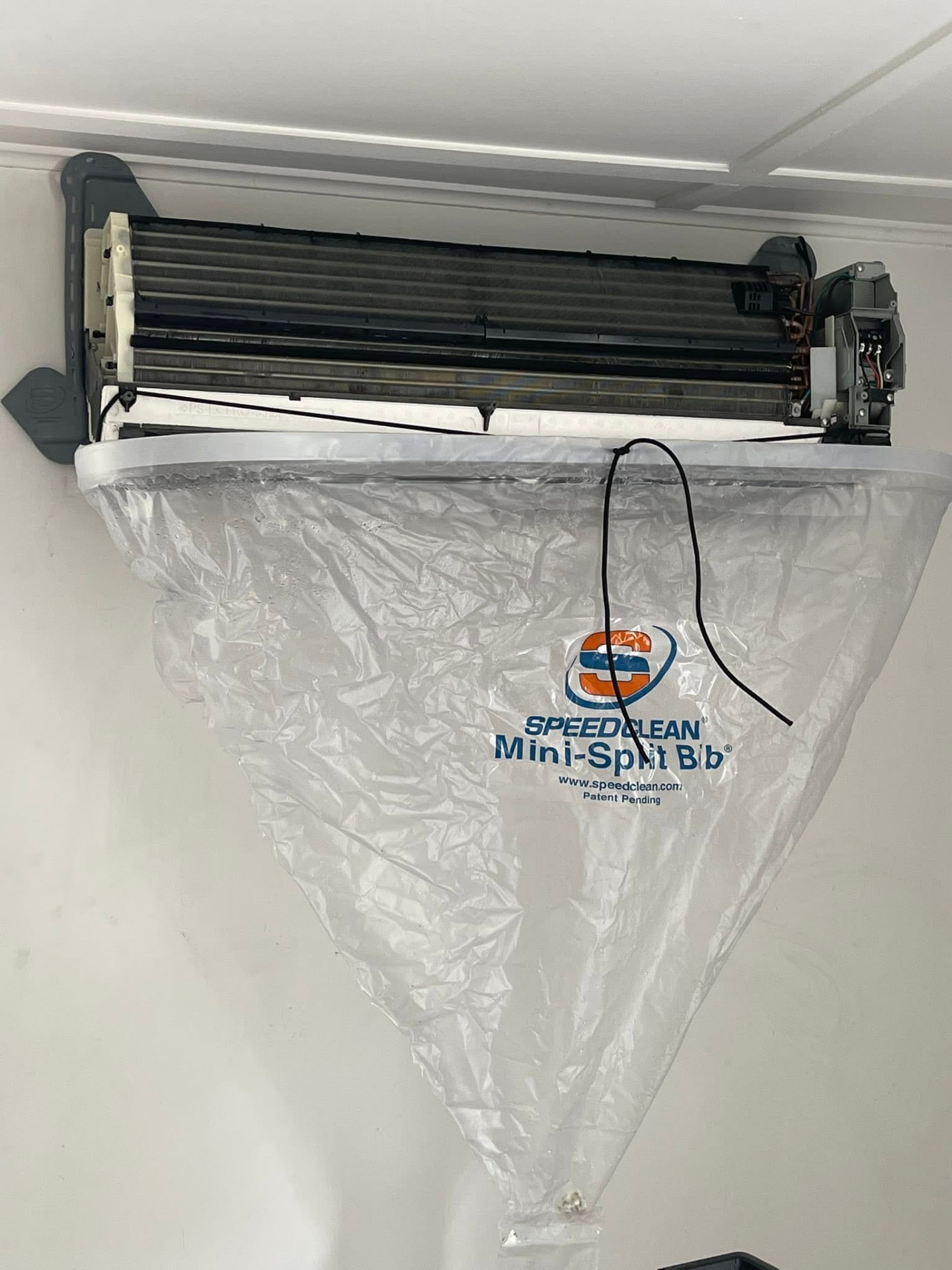 Mini split heat pump opened up with a SpeedClean cleaning bib installed to protect the wall and floor